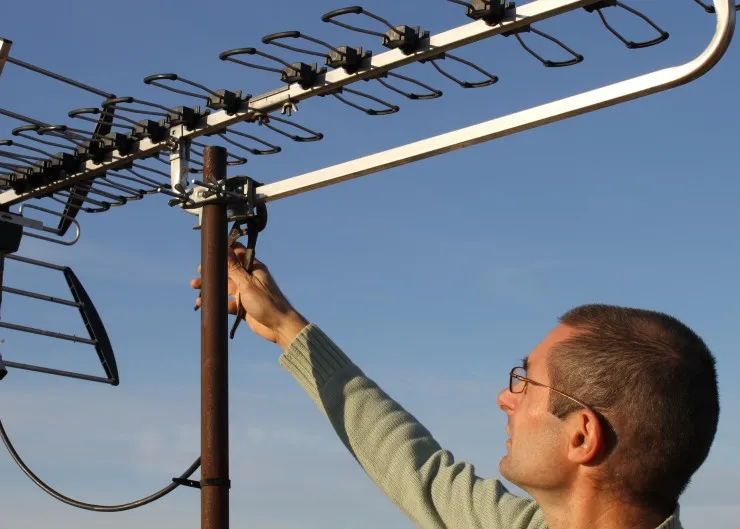Technicien antenniste réglant une antenne TV